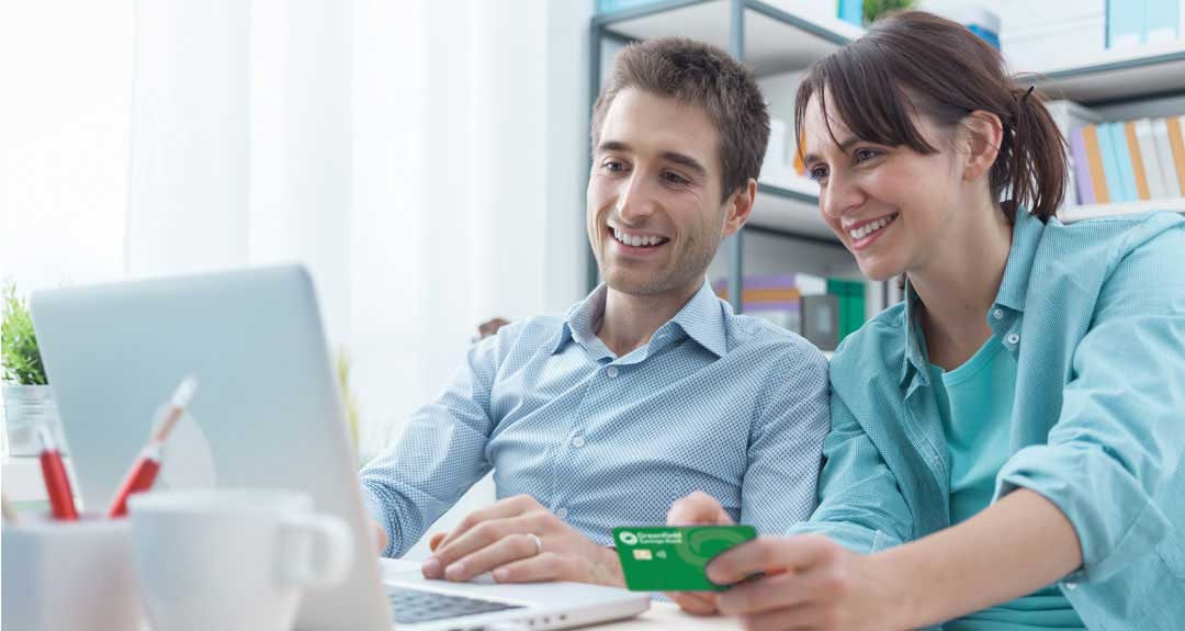 two people sitting at home looking at a laptop