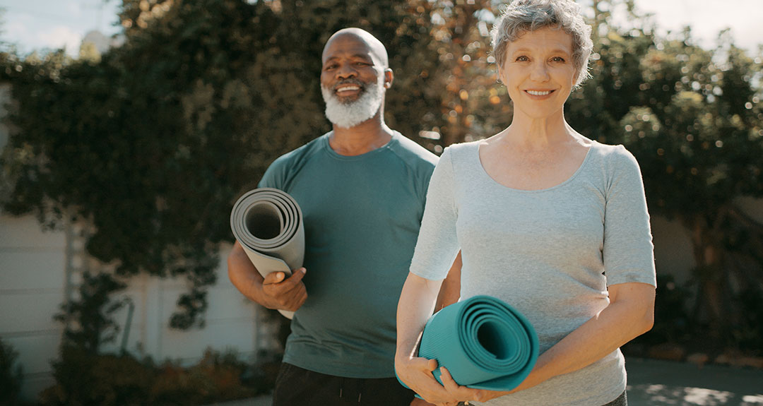 two people holding yoga mats