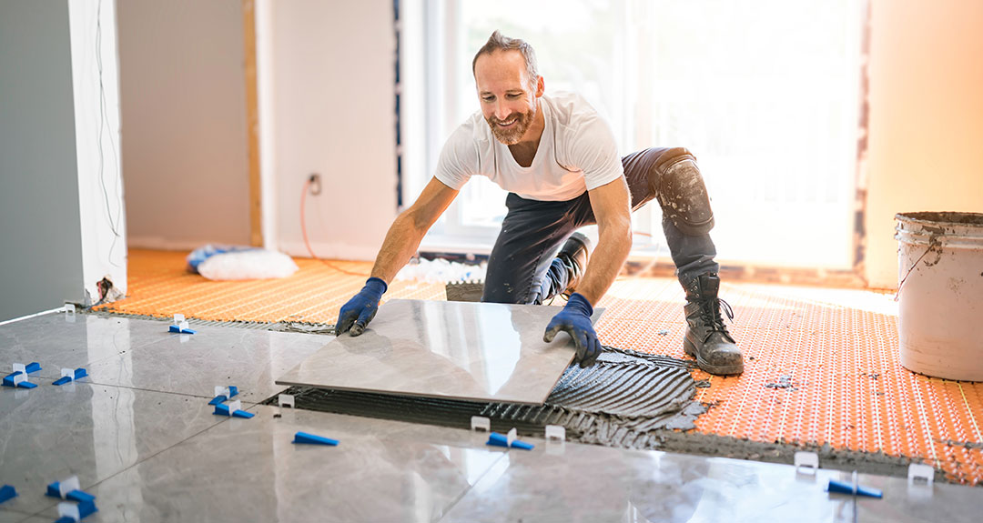 a person laying tiles in a new house