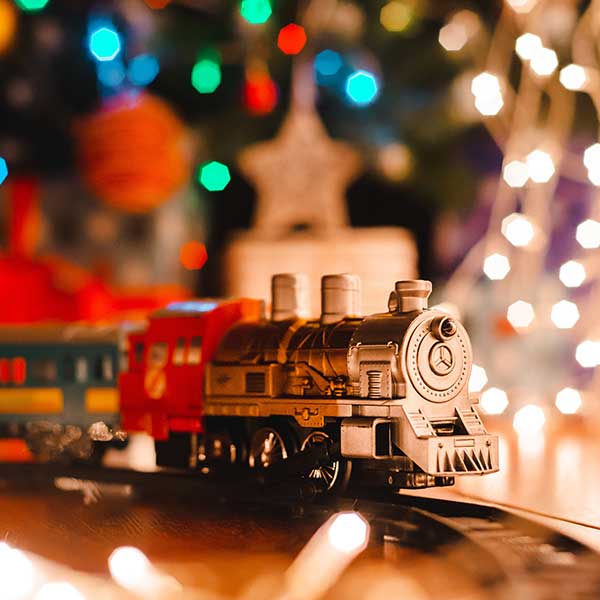 A Christmas scene with lights and a model train in the foreground.