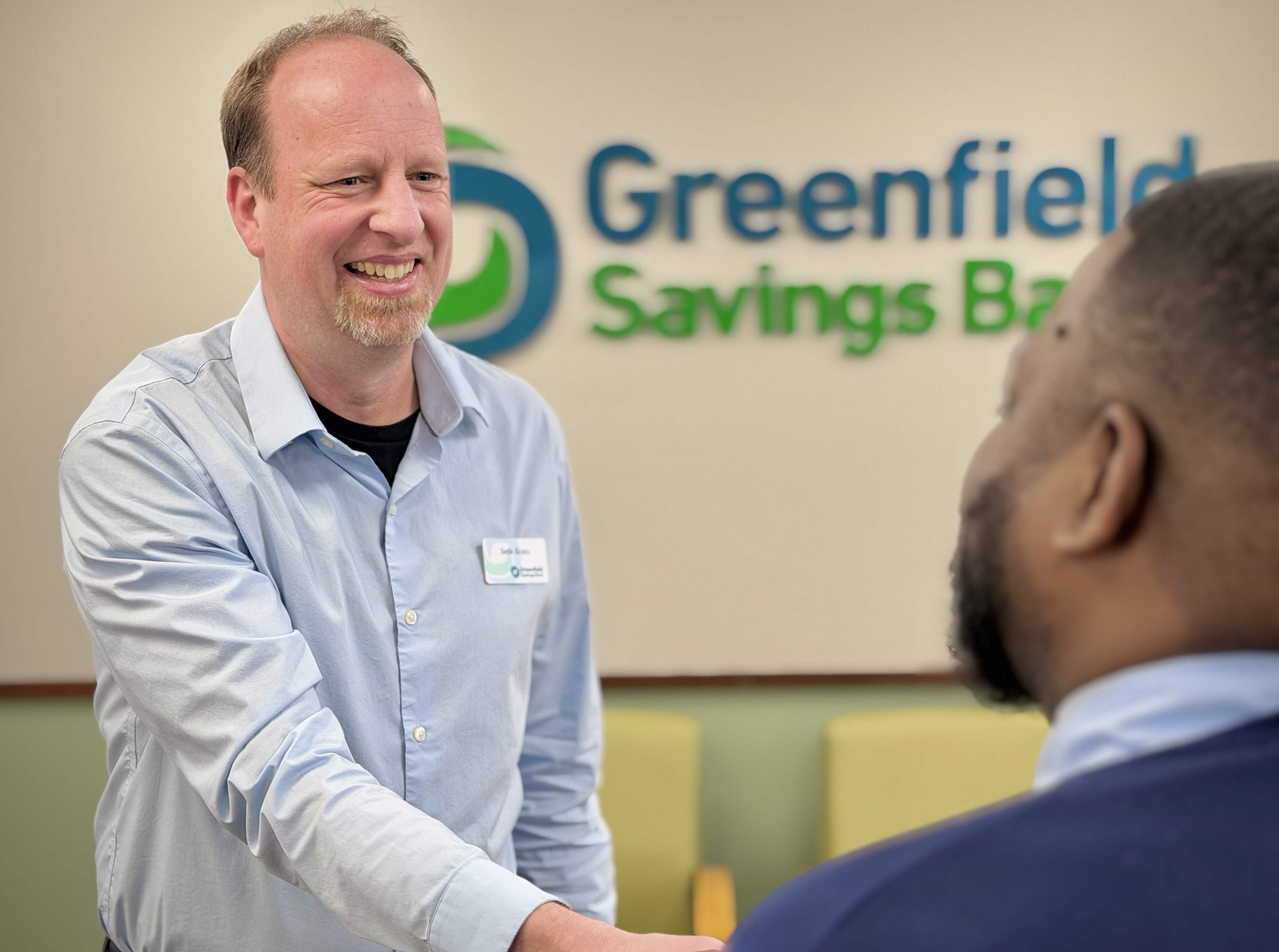 A Greenfield Savings Bank employee shakes someone's hand.