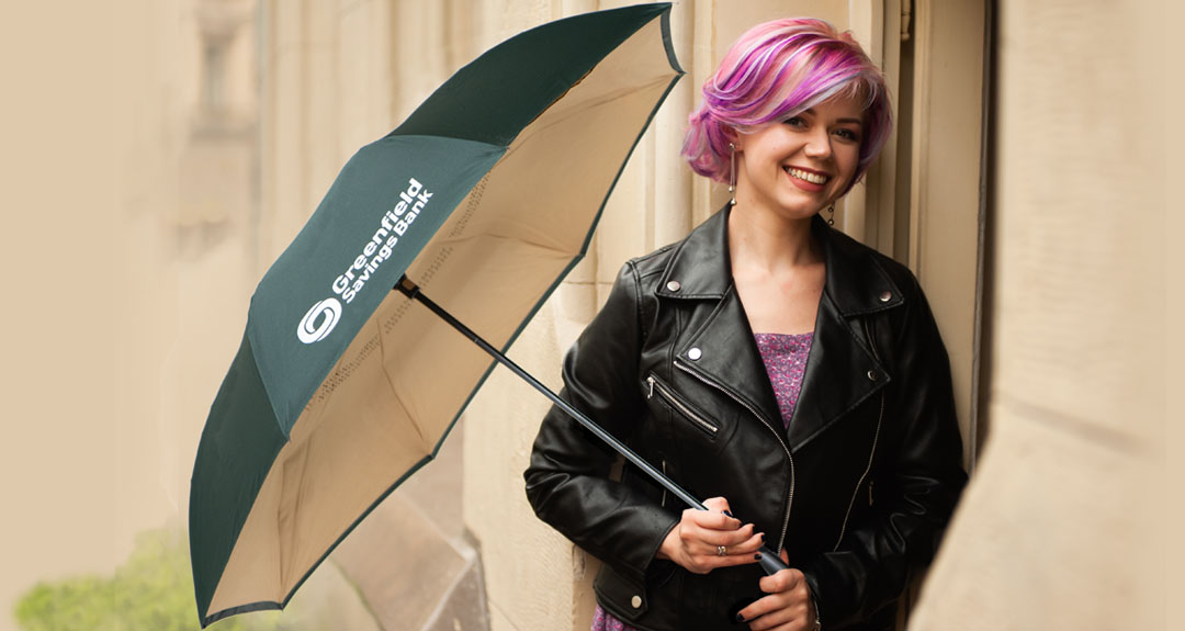 smiling woman holding the Greenfield Savings Bank umbrella