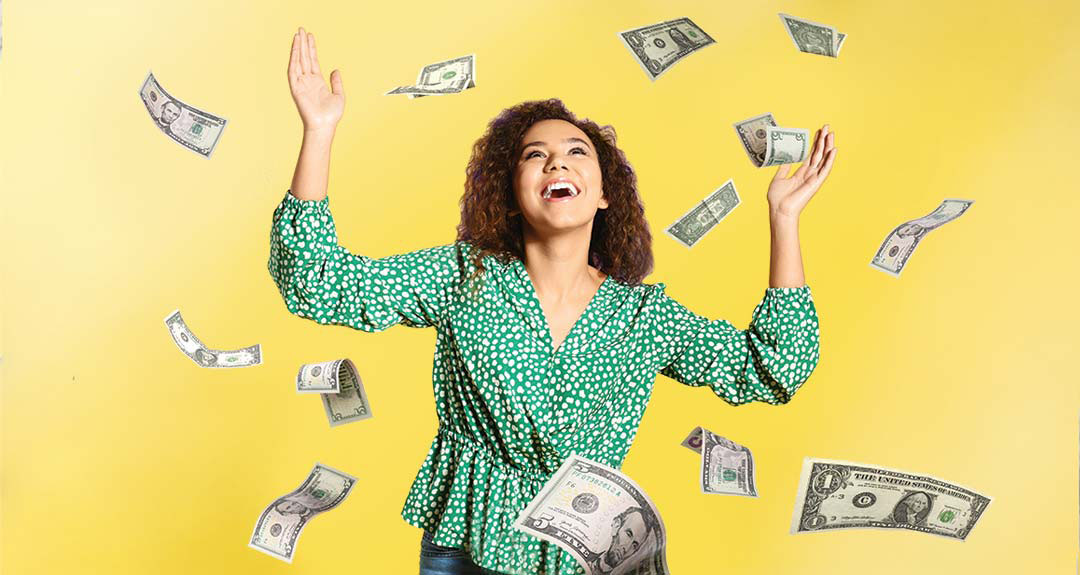 young woman, smiling, with dollar bills falling around her.
