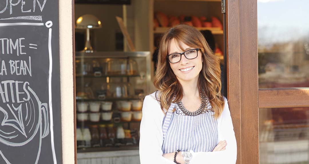 a woman standing in the doorway of a small business.