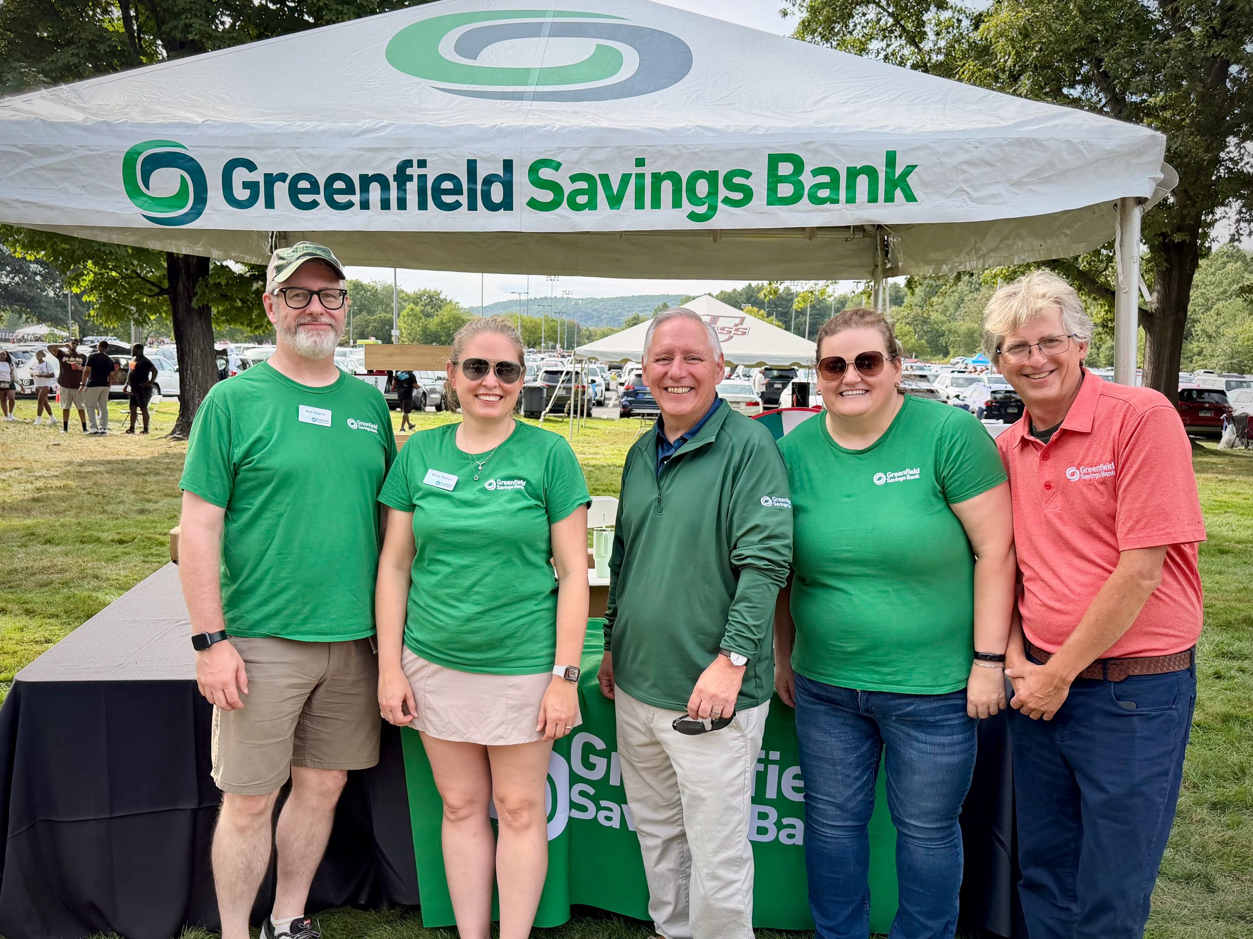 Members of the Team GSB staff posing in front of the bank's tent at a recent UMass football game.
