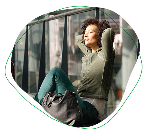 a woman relaxes in the sunlight in front of an industrial building.