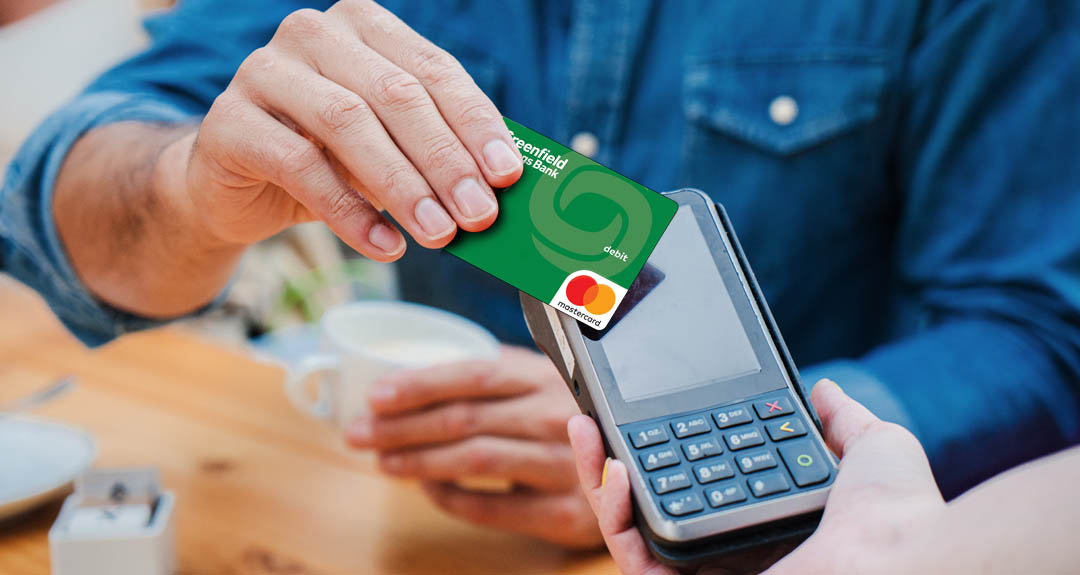 a person holds a GSB debit card to a scanner.